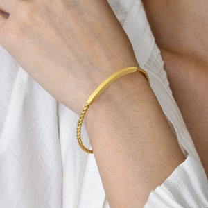 Bracelet jonc doré en acier inoxydable torsadé avec barre polie porté au poignet