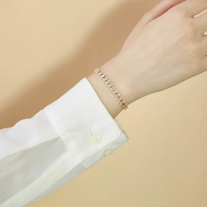 Detail eines goldenen Tennisarmbands mit ovalen Zirkonias am Handgelenk eines Models