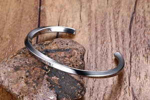 Macro view of vintage silver twisted bangle resting on a textured dark natural stone