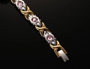 Macro view of two-tone gold and silver X-link magnetic bracelet with pink cubic zirconia