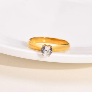Dettaglio anello in acciaio dorato con zircone a forma di cuore incastonato a griffe