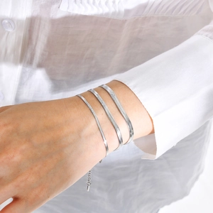 Detail shot of three silver snake bone bracelets in varying widths on a woman wrist