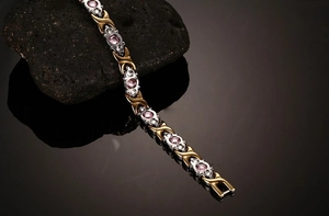 Macro detail of two-tone magnetic bracelet with pink zircon stones on black rock