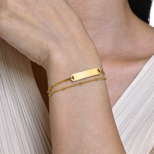 Dettaglio di un bracciale a doppio strato in acciaio inossidabile dorato con piastrina