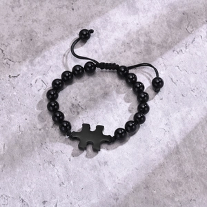 Macro view of adjustable black agate beaded bracelet with a matte puzzle piece charm