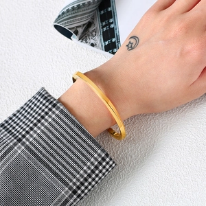 Close-up of minimalist 18K gold stainless steel open cuff bracelet worn with suit