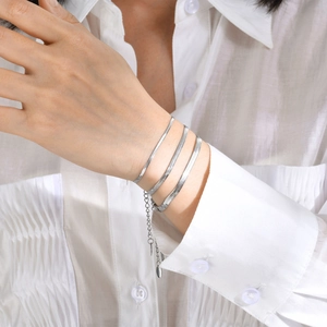 Close-up of three layered silver stainless steel snake chains on a person's wrist
