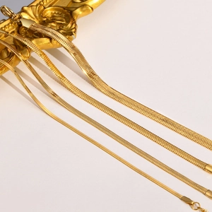 Detail of various widths gold herringbone chains with polished mirror finish texture