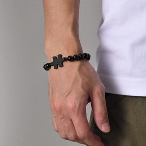 Macro detail of men's matte black beaded bracelet featuring a glossy puzzle piece charm