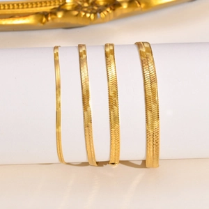 Detail showing four different widths of gold herringbone snake chains on a white display