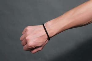 Close-up of polished black stainless steel twisted cuff bracelet on wrist