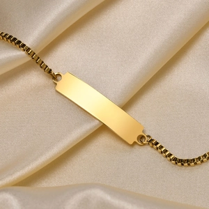 Close-up of polished gold-plated rectangle ID plate on a classic box chain bracelet