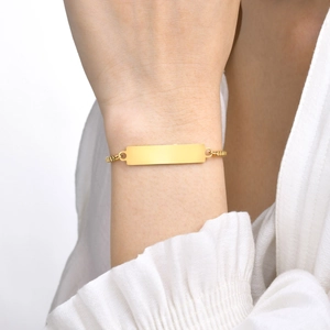 Detailed close-up of a golden box chain bracelet with a polished rectangular ID plate tag
