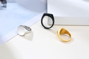 Close-up of minimalist stainless steel signet rings in gold, silver and black finishes