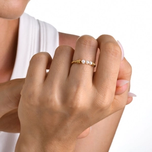Vue détaillée d'une bague torsadée plaquée or avec trois perles blanches sur un mannequin