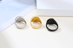 Detailed view of wide flat signet rings in polished silver, gold, and black stainless steel