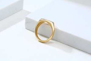 Macro view of polished 18K gold-plated signet ring showing mirror finish on marble
