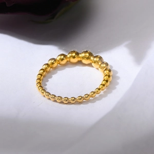 Macro shot of polished gold bead ring with minimalist graduated spheres on white surface
