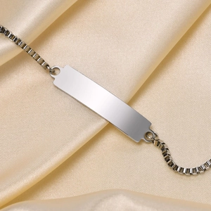 Macro detail of a polished silver box chain bracelet with a rectangle engravable ID plate