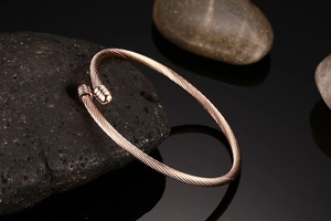 Detail of rose gold cable twist open bangle displayed on a black decorative stone