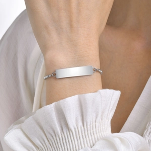 Macro detail of minimalist silver metal bar bracelet on wrist with a polished finish