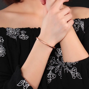 Polished rose gold stainless steel spiral twisted open bangle on model's wrist