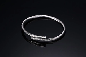 Macro detail of silver twisted cable titanium steel open bracelet with textured cylinder ends