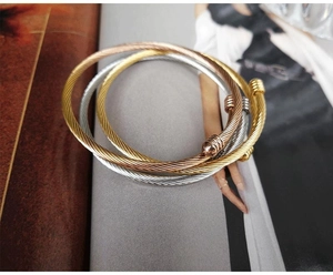 Close-up of three-tone titanium steel cable bangles with spherical end caps in various colors