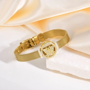 Détail d'un bracelet en maille dorée avec pendentif papillon sur un fond en soie élégant