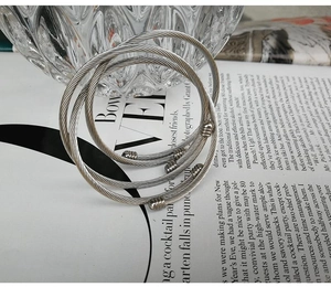 Three-piece set of silver twisted cable cuff bracelets on vintage newspaper background
