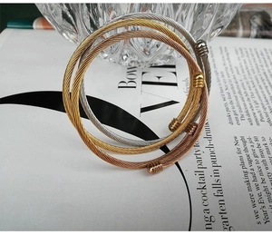 Macro detail of three-tone twisted cable wire bangles in gold, silver, and rose gold