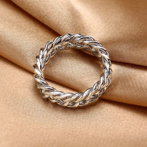Gros plan sur la bague chaîne tressée argentée sur un élégant fond en satin champagne