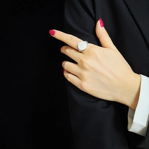 Detailed close-up of a silver-toned wide signet ring on index finger with mirror finish