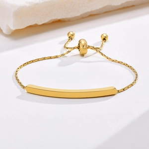 Close-up of golden adjustable bar bracelet with smooth mirror finish on stone background