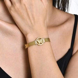 Gros plan d'un bracelet doré en maille avec un pendentif papillon pavé sur le poignet