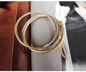 Detailed view of three twisted cable bangles in gold, rose gold and silver stainless steel