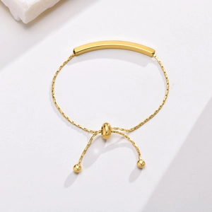 Detail of adjustable gold stainless steel bar bracelet with round slider bead closure