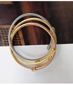 Detailed close-up of three-color twisted cable bangles in gold, rose gold and silver