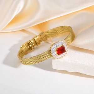 Détail d'un bracelet en maille dorée avec une grande pierre rouge et des zircons
