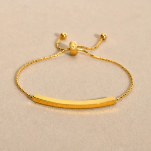 Macro shot of the polished gold arc tube and adjustable slide chain on this bracelet