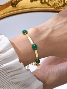 Detail of vintage gold snake chain bracelet with three green oval gemstones on a wrist