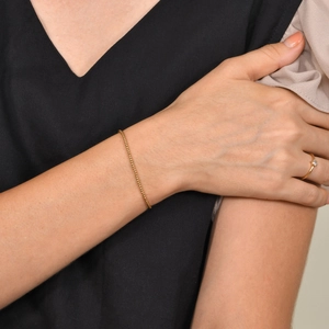 Dettaglio di un delicato bracciale a sfere dorate indossato al polso per uno stile minimale
