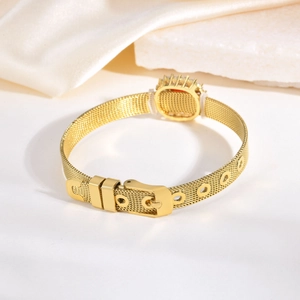 Gros plan d'un bracelet en maille dorée avec fermoir à boucle et breloque sertie de cristaux