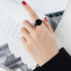Close-up of minimalist black polished signet ring worn on hand with silver background