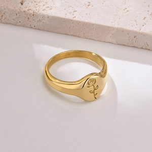 Dettaglio di un anello a sigillo dorato con incisione di rosa su piano di marmo