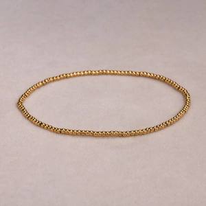 Detailansicht der glatt polierten goldenen Edelstahlperlen auf elastischem Armband