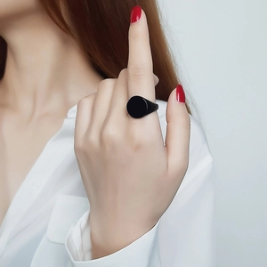 Detailed view of a minimalist black circular ring worn on a finger for styling