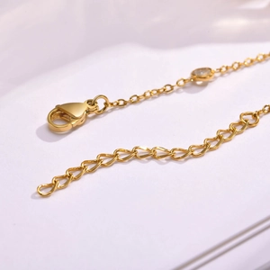 Detailed close-up of gold chain lobster clasp and adjustable extension with white zircon