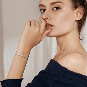 Close-up of minimalist polished silver stainless steel bar bracelet on a female wrist