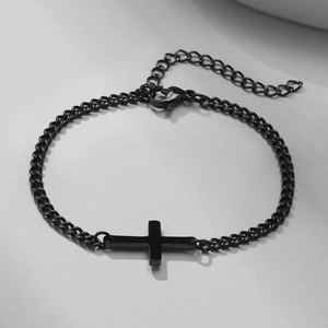 Macro view of black stainless steel curb chain bracelet with minimalist cross detail